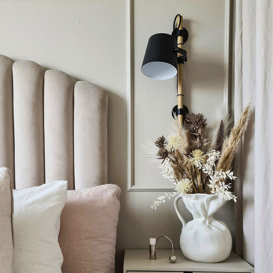Interiørbilde av Espresso vegglampe med tiltbart lampehode festet på en loddrett stang laget i sort metall  og naturlig treverk - Aneta belysning