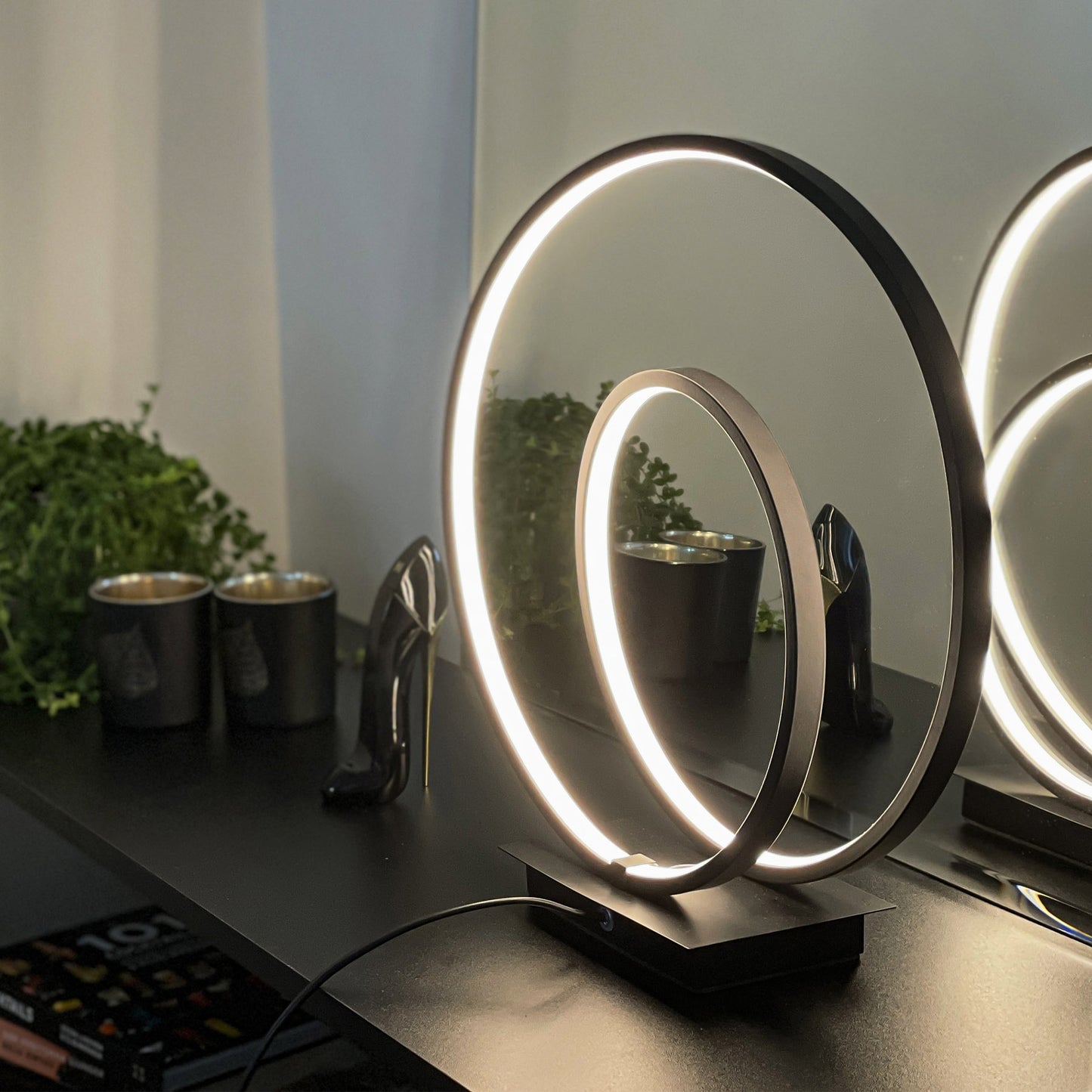 Loop bordlampe på en sort hylle, formet som to loops med integrert LED-lys laget i svart metall 3-stegs dimbar - Aneta belysning