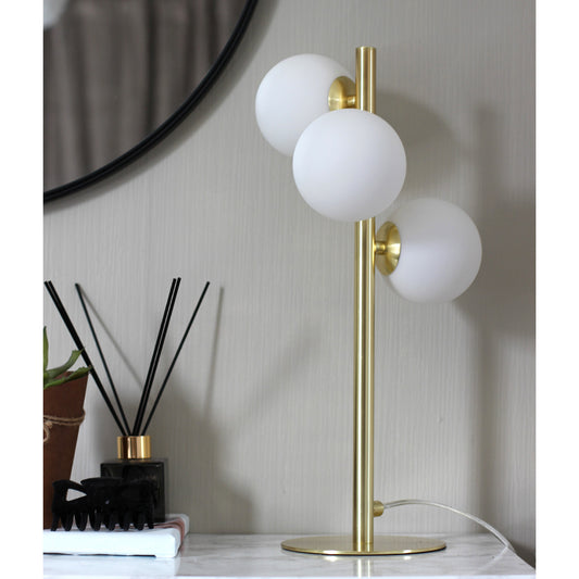 Interiørbilde av Molekyl bordlampe i matt messing og tre opale glasskupler festet langs lampefoten - Aneta belysning