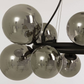 Nærbilde av kuplene på Molekyl taklampe pendel med 10 sotede glasskupler festet på en rund ramme i sort metall - Aneta belysning