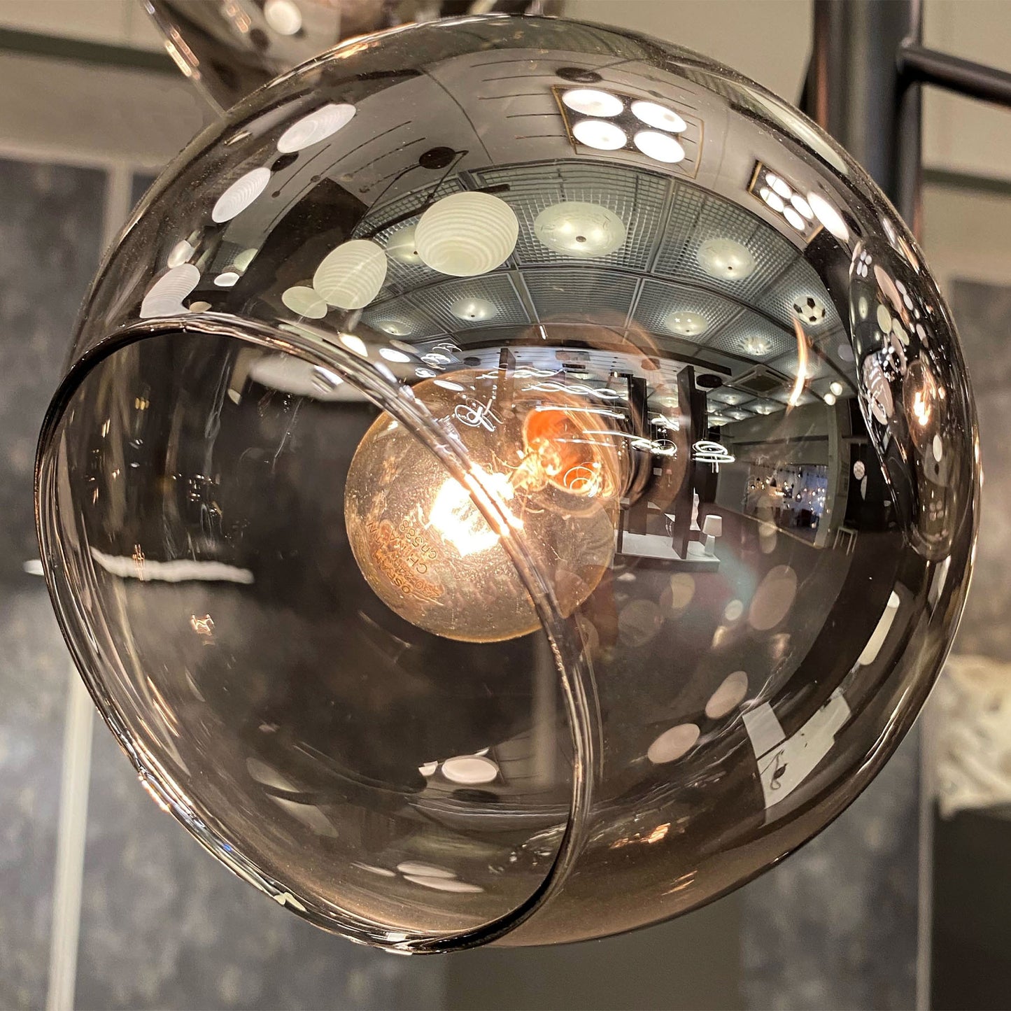 Nærbilde av kuppel til Atom taklampe pendel med fem sotede glasskupler og sort metall E14 - Aneta Belysning