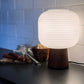 Interiørbilde av Aura bordlampe med brunbeiset lampefot i treverk og hvit rillet glasskjerm rund- Aneta belysning