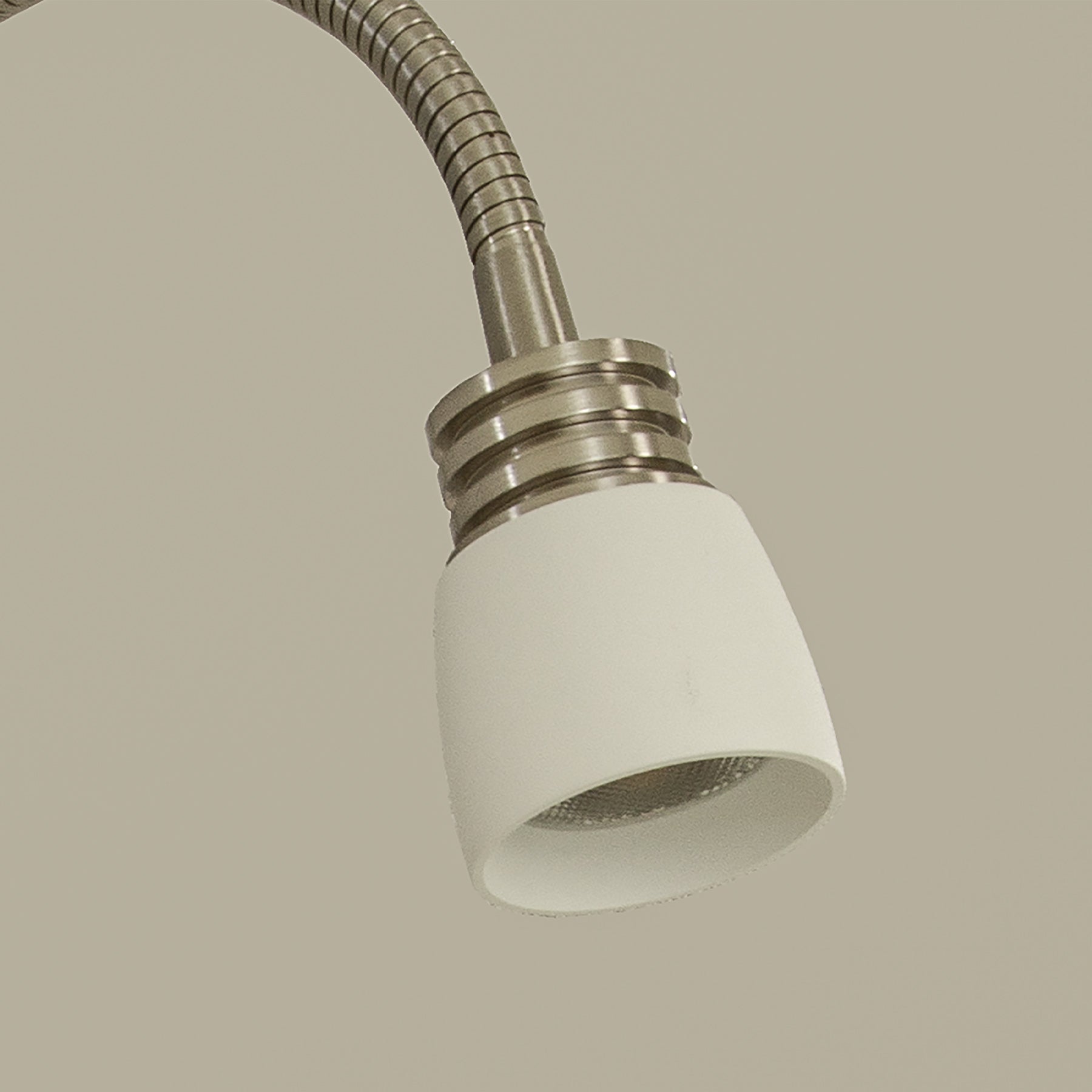 Nærbilde av lampehodet til Eketorp sengelampe til montering på gavl, laget i hvit metall og stål med justerbar arm og integrert LED-lys - Aneta belysning