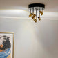 Gusto spotlight taklampe lysende i en stue med fem justerbare spotter i ulik høyde plassert på en rund takplate, laget i sort metall og messing - Aneta belysning