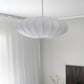 Mamsell taklampe pendel hengende på et soverom, rund med diameter 45cm trukket i hvit tekstil rundt en ramme i hvit metall - Aneta belysning