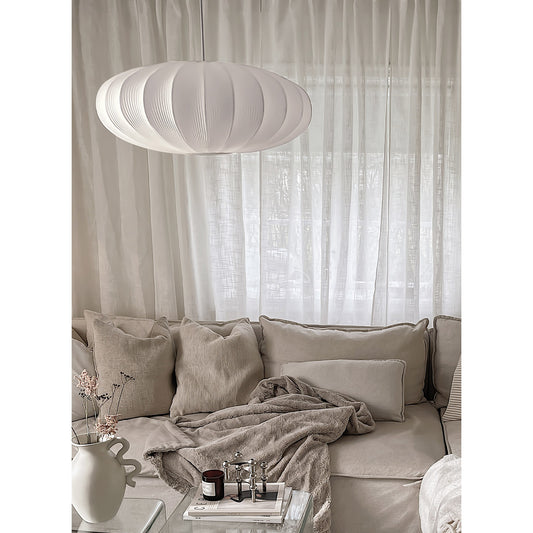 Mamsell taklampe hengende i en stue med beige interiør, en rund pendel med diameter 55cm trukket i hvit tekstil rundt en ramme i hvit metall - Aneta belysning