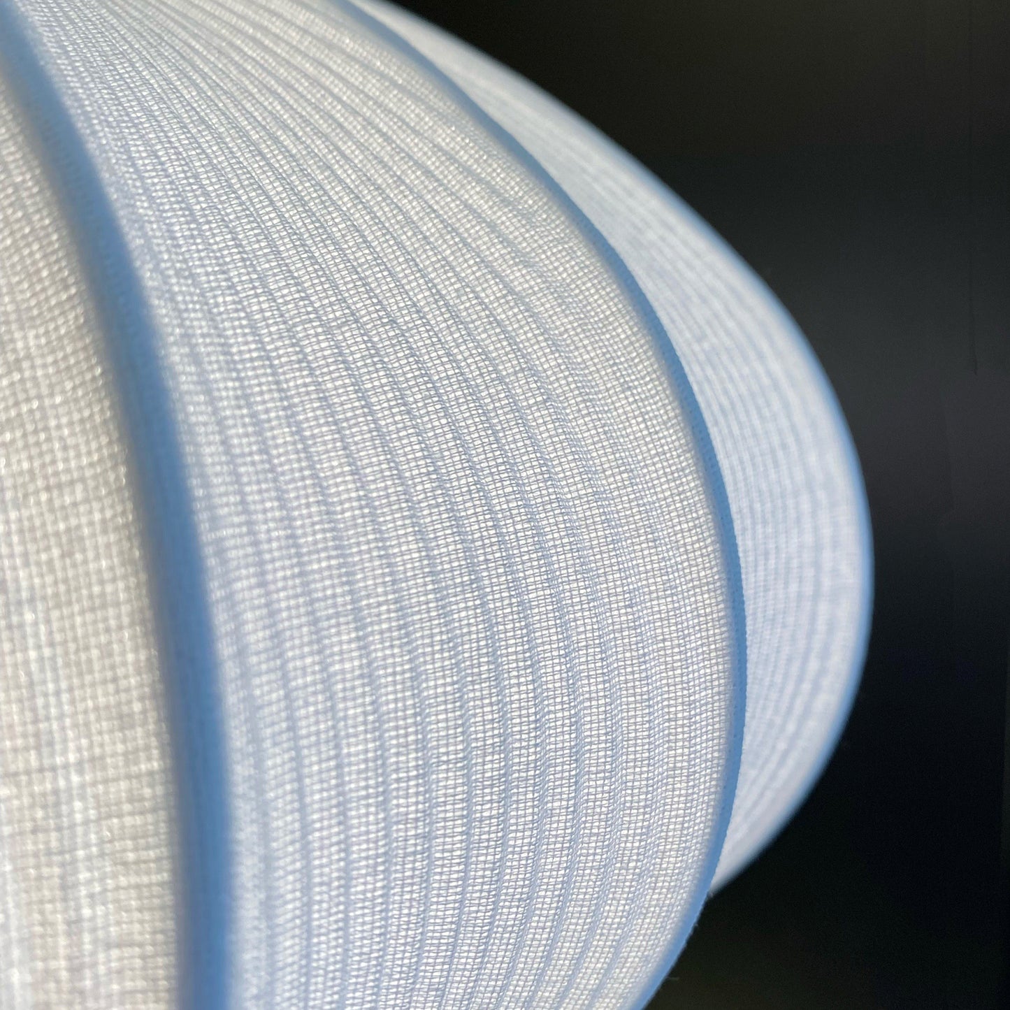 Nærbilde av hvordan lyset skinner gjennom det hvite stoffet på Mamsell takpendel med diameter 55cm - Aneta belysning