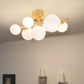 Molekyl taklampe plafond lysende i en stue, laget i messing metall og med syv opale glasskupler festet langs en rett stang - Aneta belysning
